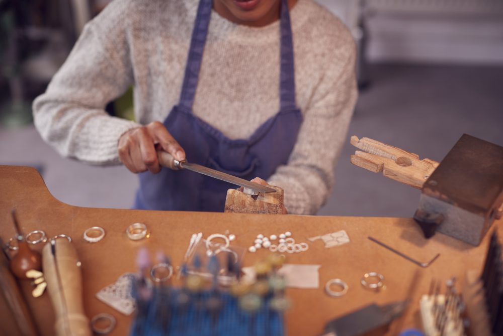Close Up Of Female Jeweller Working On Ring With File In Studio