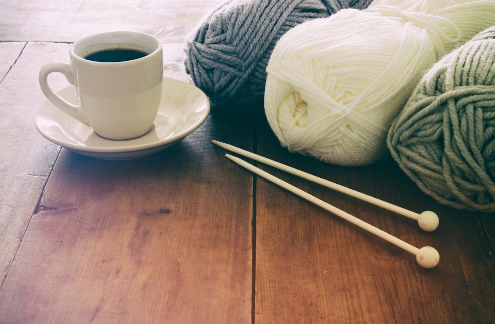 warm and cozy yarn balls of wool and hot cup of coffee on wooden table